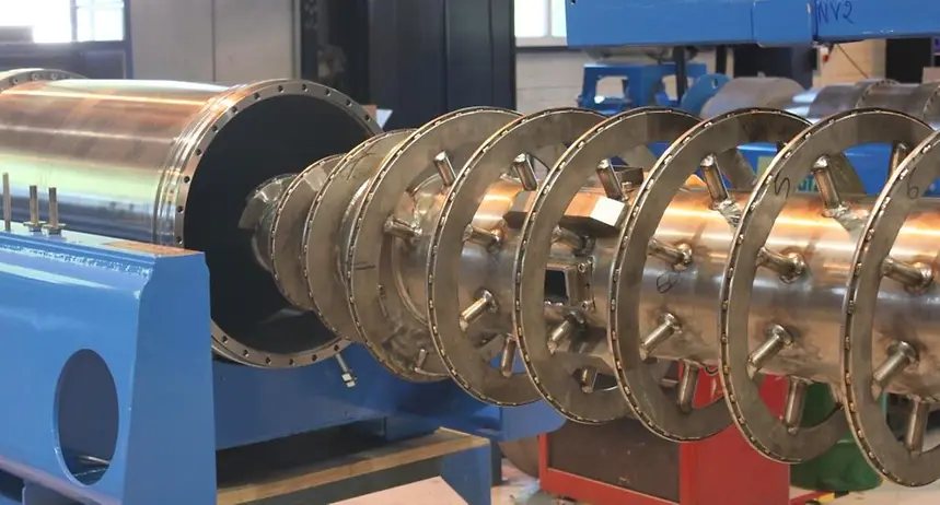 Tornillo transportador de una centrífuga decanter desmontado fuera del rotor, sobre el bastidor en taller.